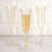 Elegant gold champagne flutes with bubbles on a marble surface.
