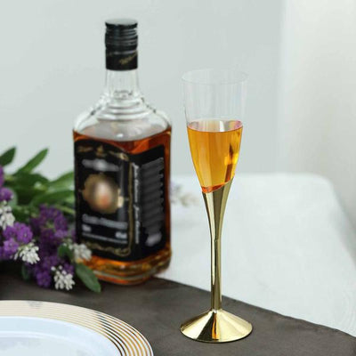 Elegant gold-rimmed champagne flute with amber liquid and a bottle in the background.