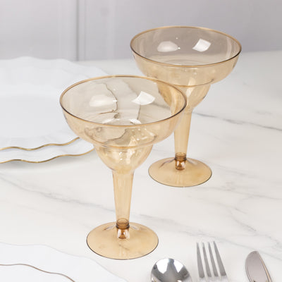 Two elegant amber margarita glasses on a marble table.