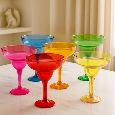 Colorful margarita glasses in pink, red, yellow, green, and blue on a marble surface.