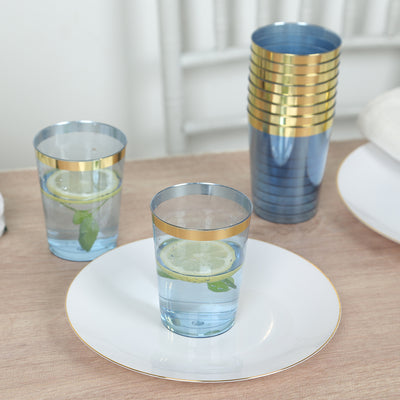Blue glass tumblers with gold rims and lemon slices on a wooden table.
