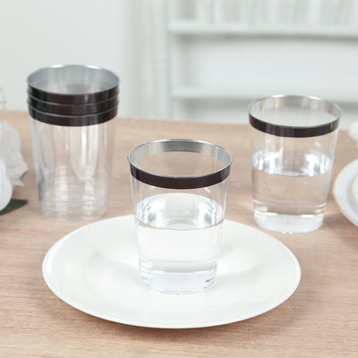 Clear glasses with black rims on a wooden table with a white plate.