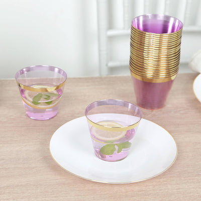 Purple acrylic cups with gold rims, filled with pink lemonade and garnished with lemon.