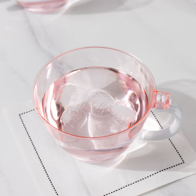 Transparent pink cup filled with water and ice on a white napkin.