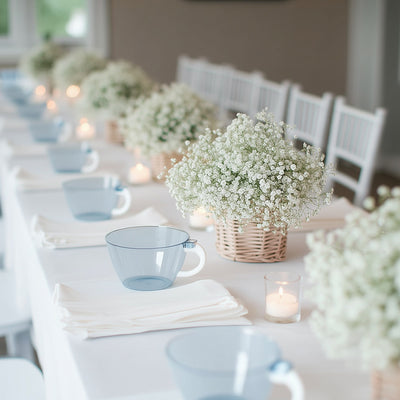 Elegant blue cups set on a dining table with white flowers and candles.