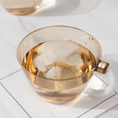 Transparent cup with iced drink and ice cubes on a napkin.