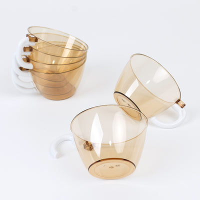 Set of transparent amber coffee mugs stacked on a white background
