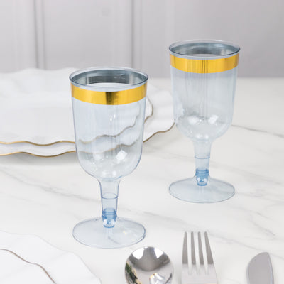 Elegant blue glasses with gold rims on a marble table setting.
