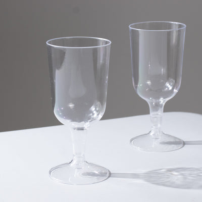 Clear plastic wine glasses on a plain background.