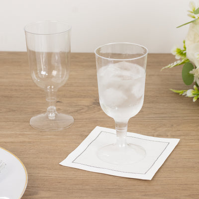Two elegant drinking glasses on a wooden table with a napkin.