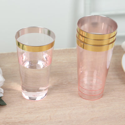 Pink plastic cups with gold rims, displayed on a wooden table.