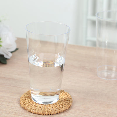 Clear glass of water on a woven coaster against a wooden table.