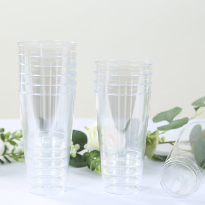 Stacked clear plastic cups on a table with greenery.