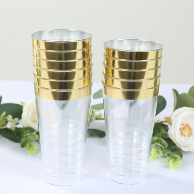 Stack of clear plastic cups with gold rims on a table with greenery.