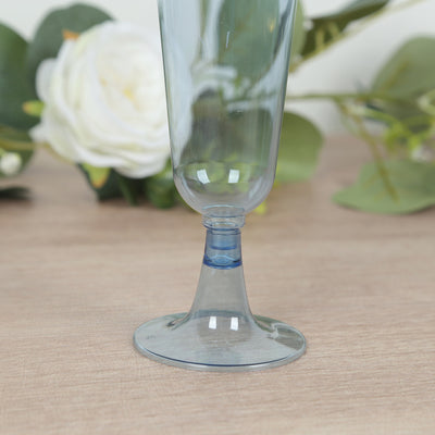 Blue glass champagne flute on a wooden surface with floral background.
