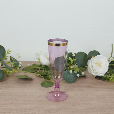 Pink champagne flute with gold rim against a light background.