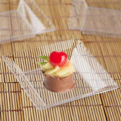 Clear dessert plate with chocolate-covered treat and fruit garnish.