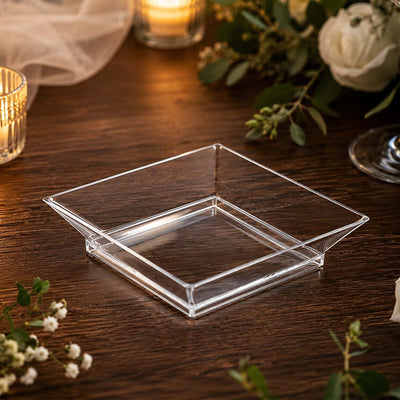 Clear square acrylic serving tray on wooden table with candles and flowers