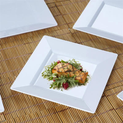 Grilled salmon on a bed of salad in a white square plate.