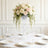 Elegant floral arrangement in a clear vase on a dining table setting.