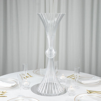 Elegant clear glass vase centerpiece on a dining table with white linens.