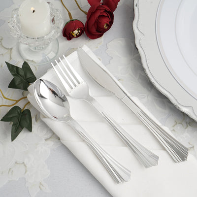 Elegant silver cutlery set on a white napkin with decorative flowers.
