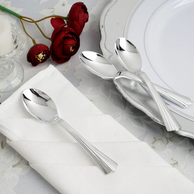 Set of elegant silver spoons on a white table setting with roses.