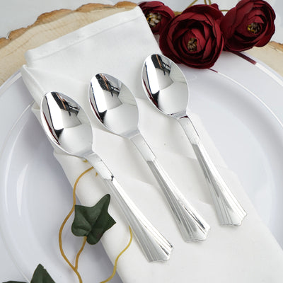 Three elegant stainless steel spoons resting on a napkin with decorative flowers.