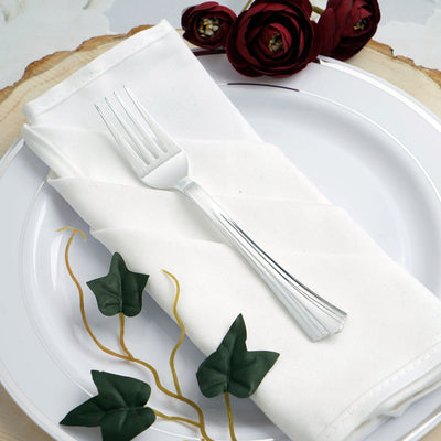 Elegant dining fork on a white napkin with decorative greenery and flowers.