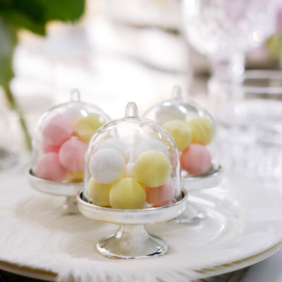 Pastel candy in elegant glass cloches on a plate.