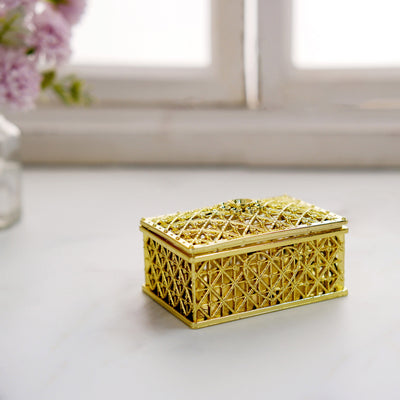 Gold decorative box with intricate design on a plain surface.