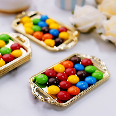 Colorful chocolate candies in ornate trays on a marble surface.