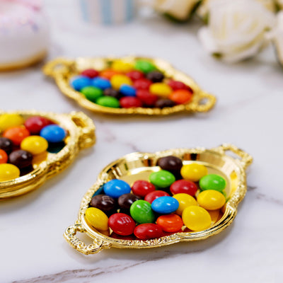 Colorful candies in ornate gold trays on a marble surface.
