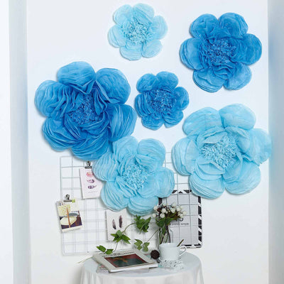 Blue tissue paper flowers for wall decor in various sizes.