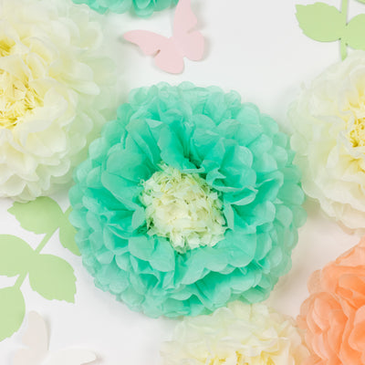Colorful tissue paper flowers in mint, peach, and cream on a white backdrop.