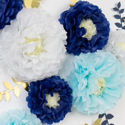 Colorful tissue paper flowers in blue, white, and aqua on a white backdrop.