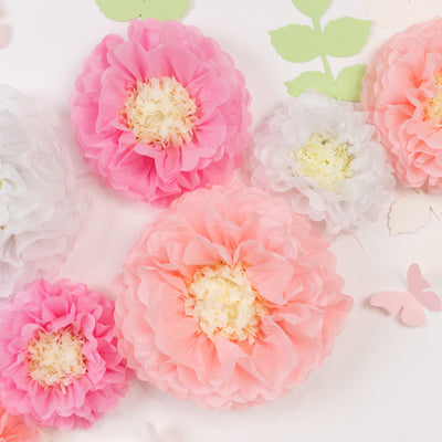 Colorful tissue paper flowers in pink, coral, and white on a white background.