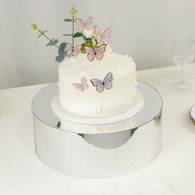 Elegant white cake adorned with butterfly decorations on a mirrored stand.
