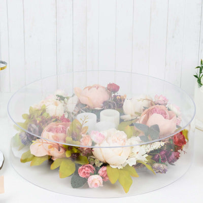 Floral arrangement in a clear display dome with candles and decorative accents.