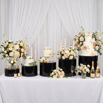 Elegant wedding dessert table with floral cake display, candles, and champagne.