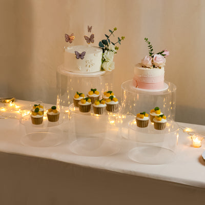 Elegant dessert display with cakes and cupcakes on clear pedestals.