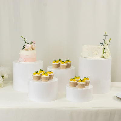 White display pedestals with cakes and cupcakes arranged elegantly.