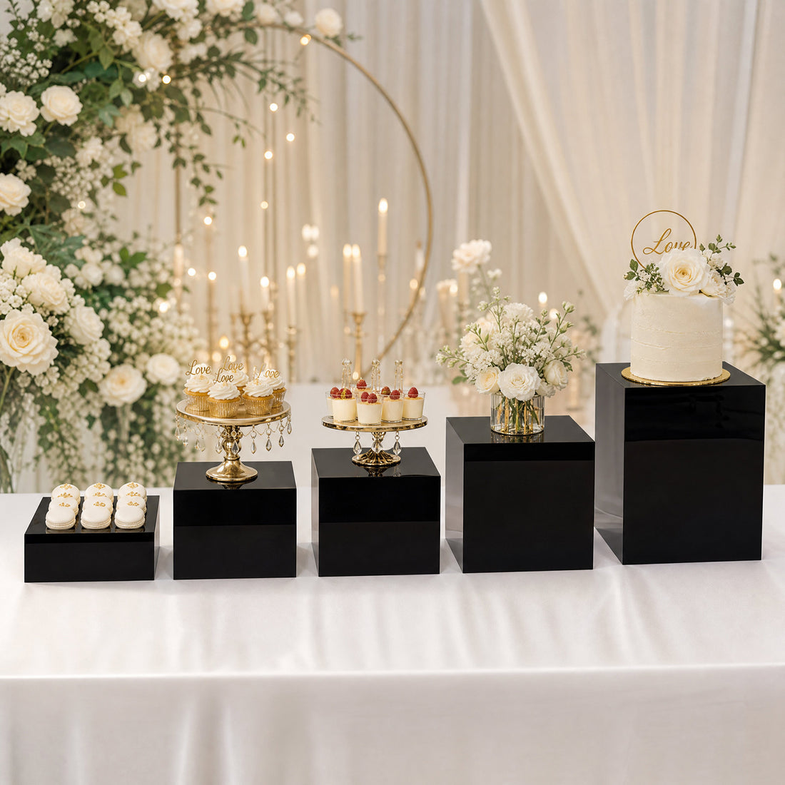 Elegant wedding dessert table with cake, cupcakes, macarons, and white floral decor