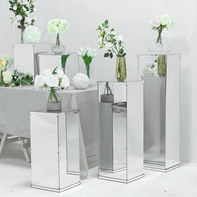 Mirrored flower pedestal stands with vases and floral arrangements