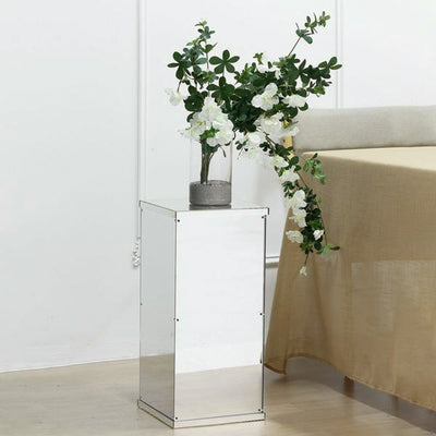 Reflective side table with flowers in a vase, styled in a modern interior.