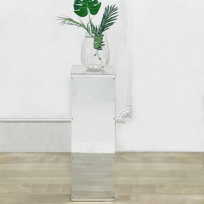 Mirrored plant stand with glass vase and greenery on top
