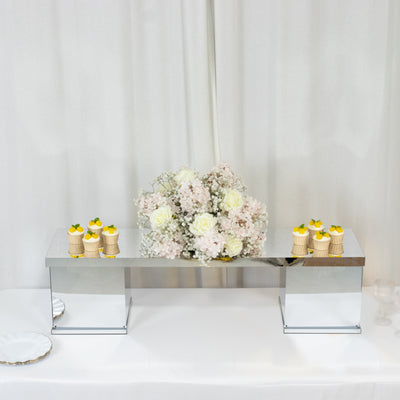 Elegant dessert display with cupcakes and floral arrangement on a mirrored table.
