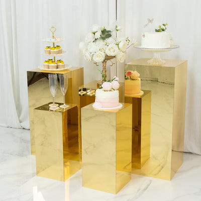 Elegant gold display stands with cakes and desserts at an event.