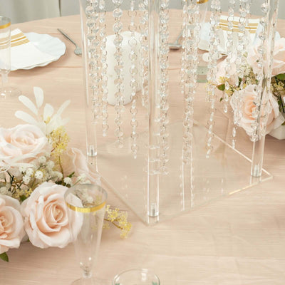 Elegant acrylic centerpiece with hanging beads and soft pink rose arrangements.