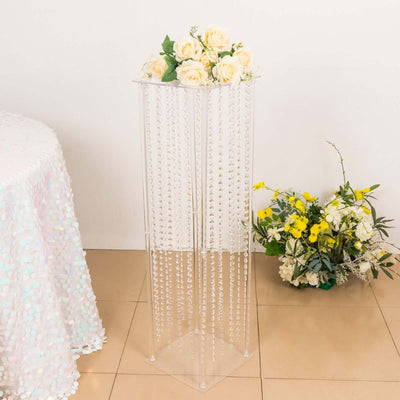 Clear acrylic flower stand with cascading beads and roses on top.